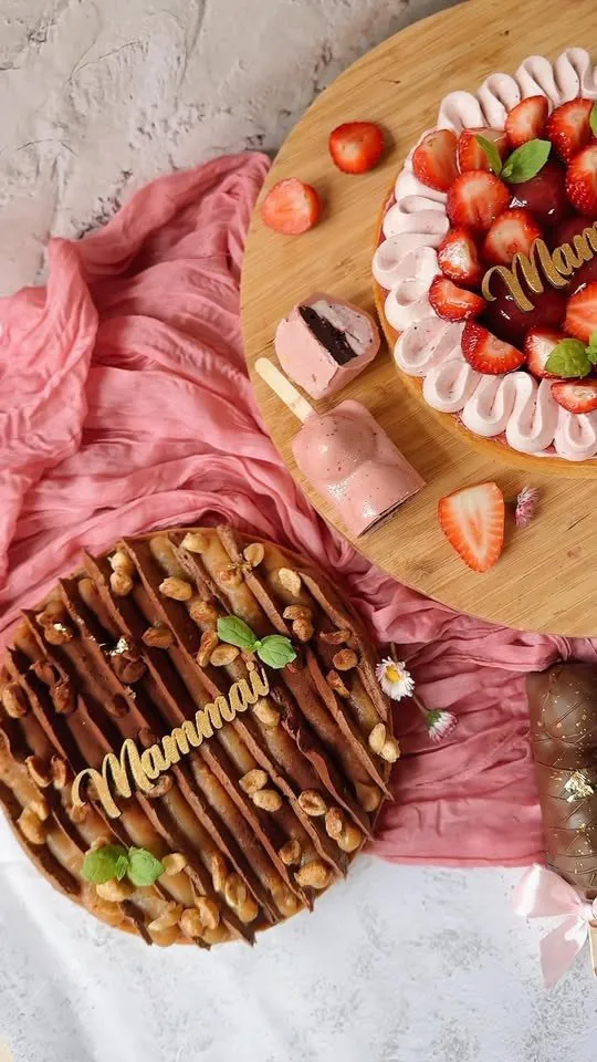 Divas tortes ar uzrakstu „Mammai” – viena ar zemenēm, otra ar šokolādi un riekstiem